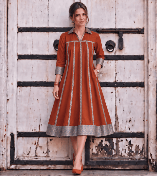 Woman wearing Zinniars Mannat Rust Brocade Flare Midi Dress with silver trim.