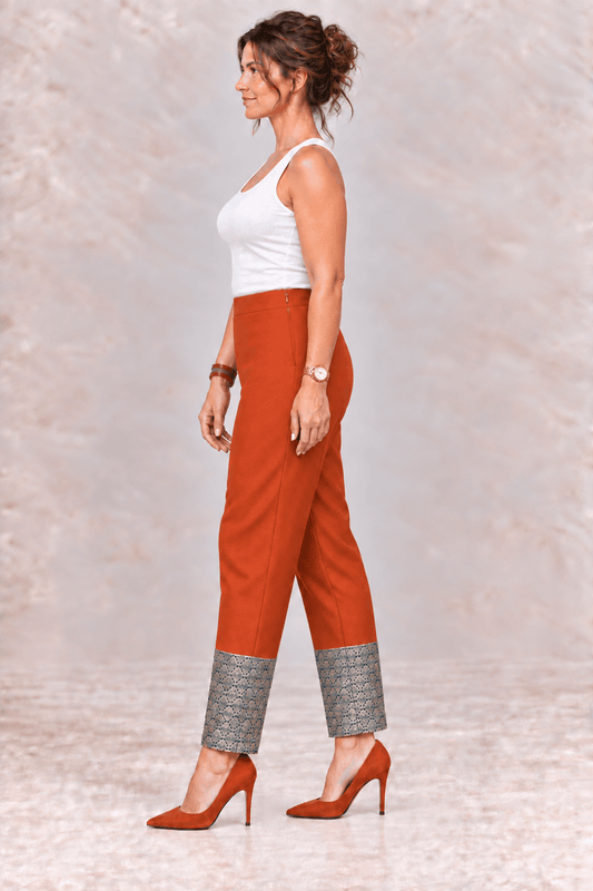 Woman wearing Zinniars Aria rust relaxed pencil pants with a decorative brocade hem.